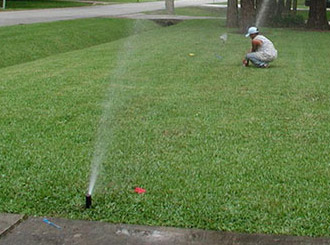 a tech is making some adjustements on a sprinkler system